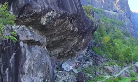 200-year-old wooden structures are built directly under a massive, overhanging rock formation
