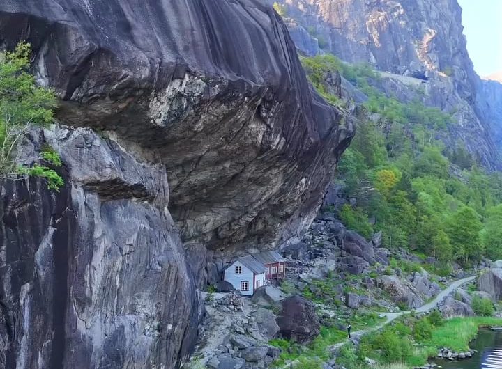 200-year-old wooden structures are built directly under a massive, overhanging rock formation