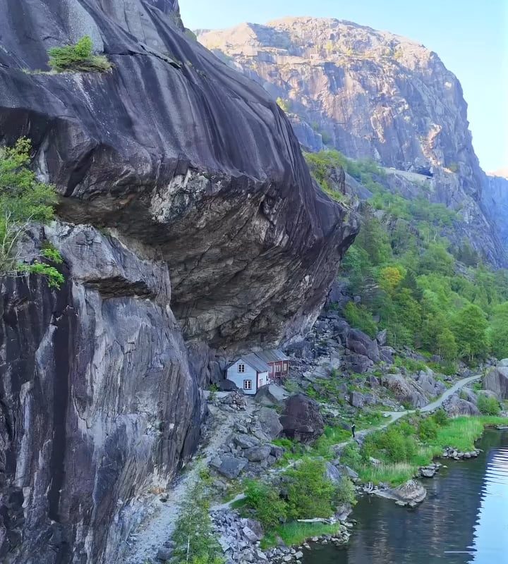 200-year-old wooden structures are built directly under a massive, overhanging rock formation