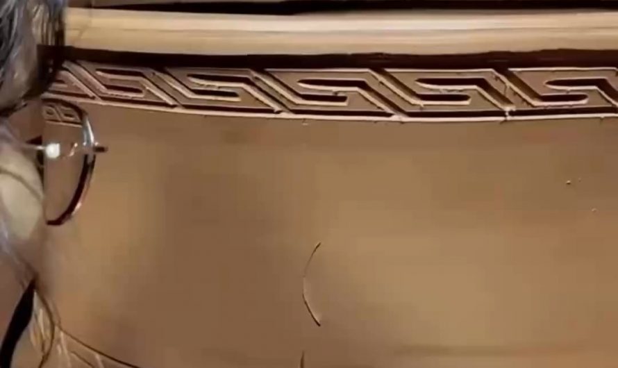 Carving out a flower pattern on a wet clay pot