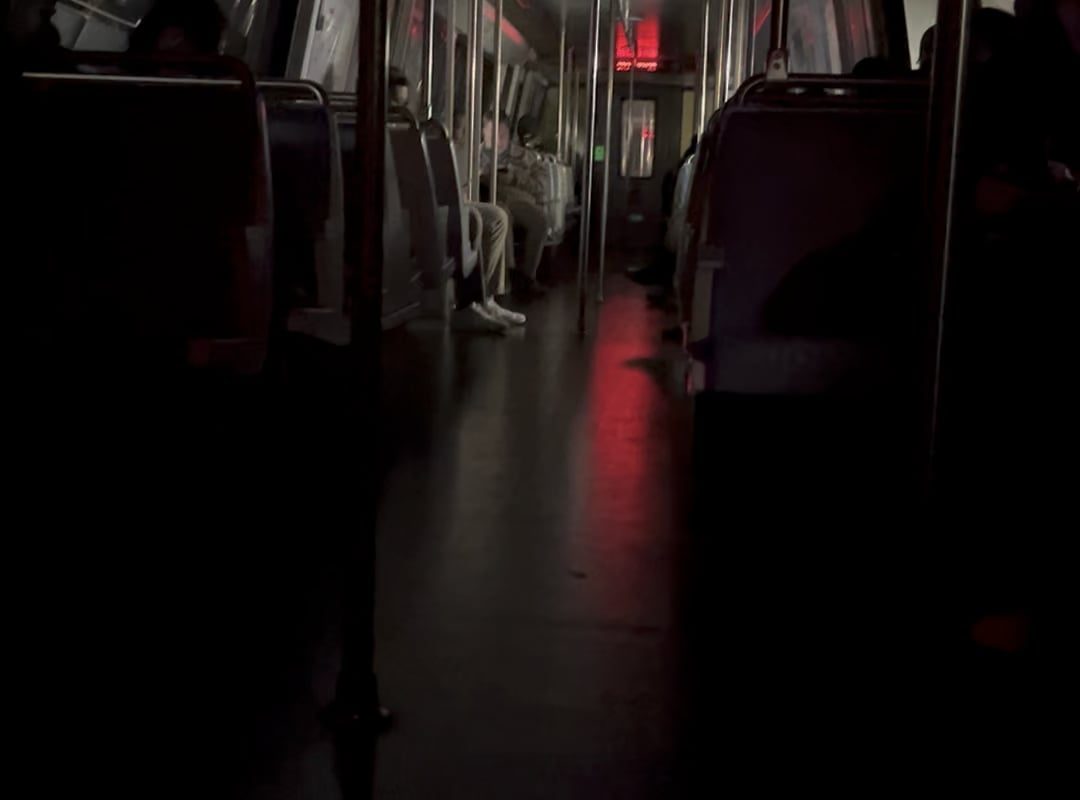 Dark Subway Car traveling through a sparely lit tunnel