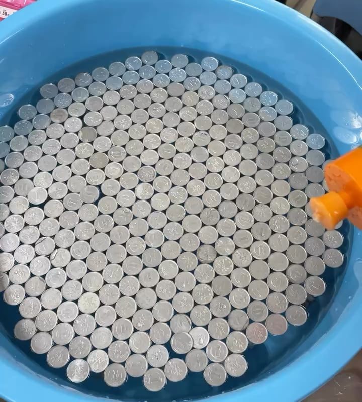 Floating coins start sinking when the surface tension is broken