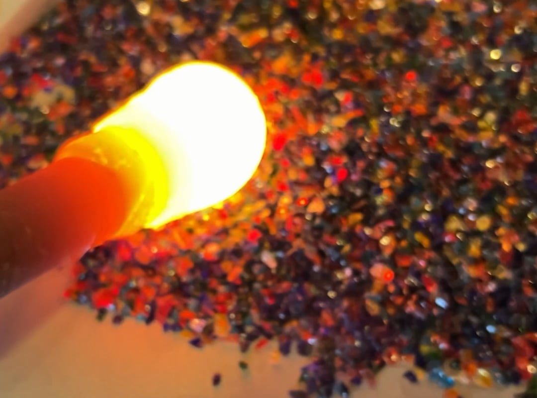 Rolling through pieces of colored glass to make an ornament.