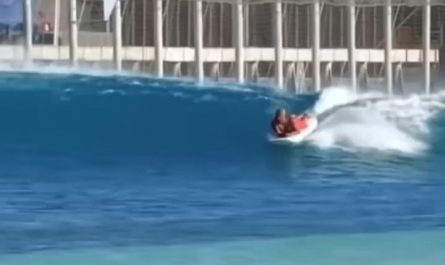 Surf Instructor Balances While Teaching a Student on His Own Board