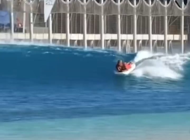 Surf Instructor Balances While Teaching a Student on His Own Board