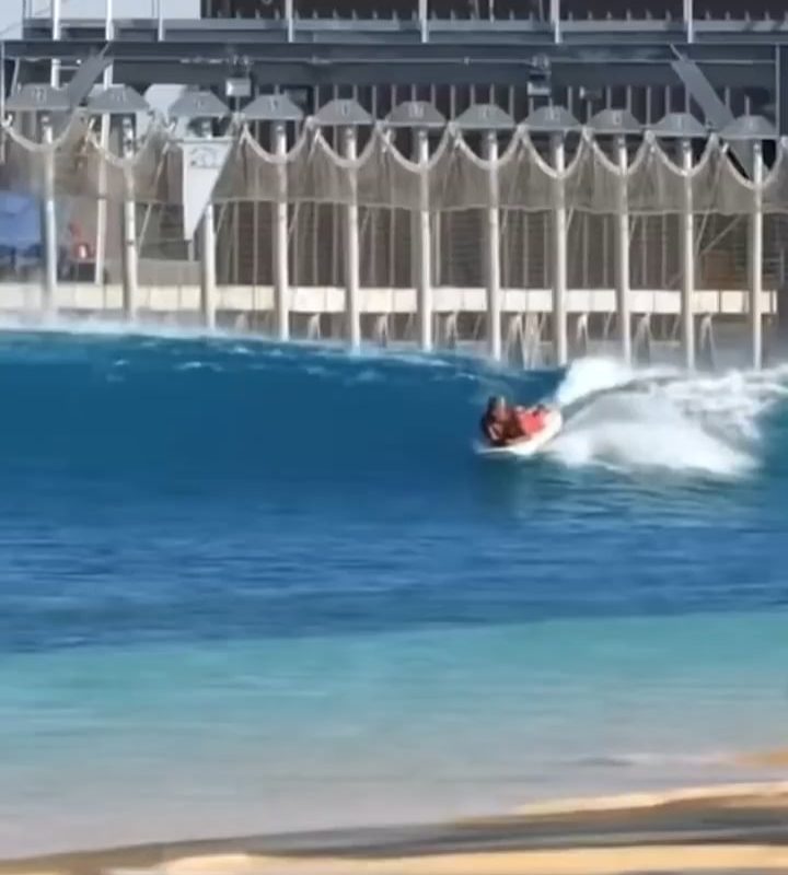 Surf Instructor Balances While Teaching a Student on His Own Board