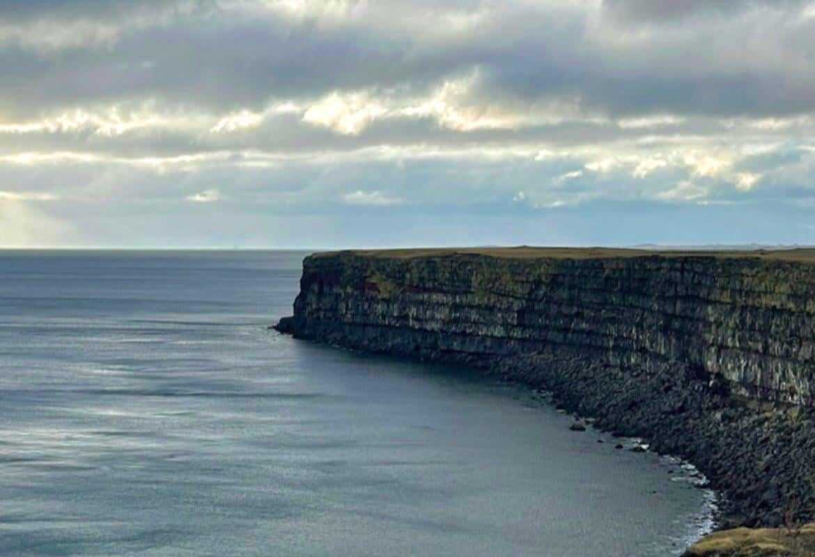 The sea and the cliff create a straight line in the center of the photo