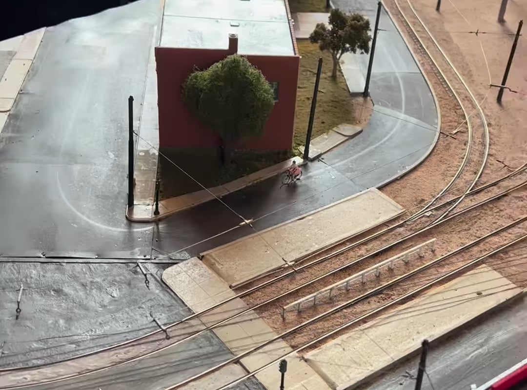 This tiny cyclist pedaling around the block, while a tram glides past on its way through the city