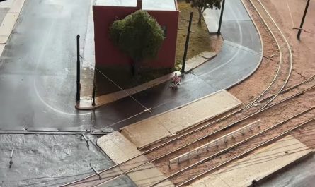 This tiny cyclist pedaling around the block, while a tram glides past on its way through the city