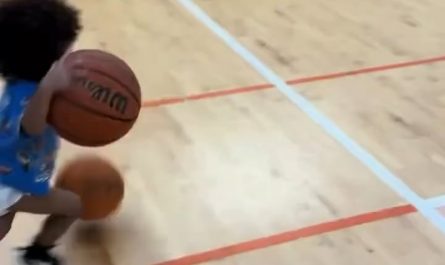 Toddler dribbling two basketballs on either hand