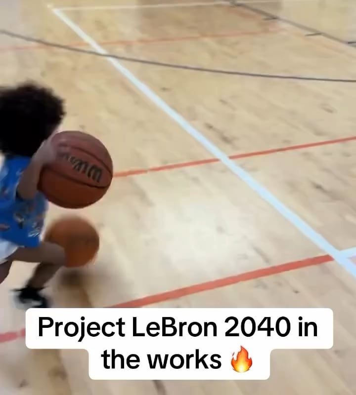 Toddler dribbling two basketballs on either hand