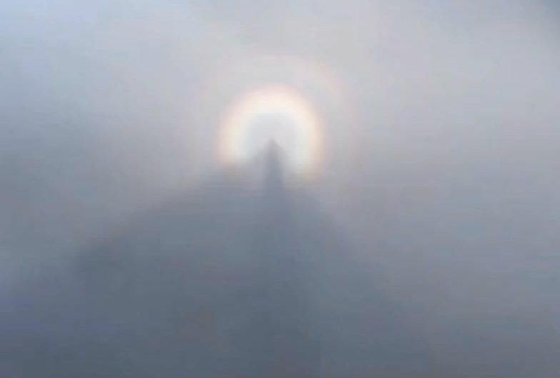 A hiker captures his own shadow floating in the mountain mist, surrounded by a bright solar halo. An unusual but completely natural phenomenon.