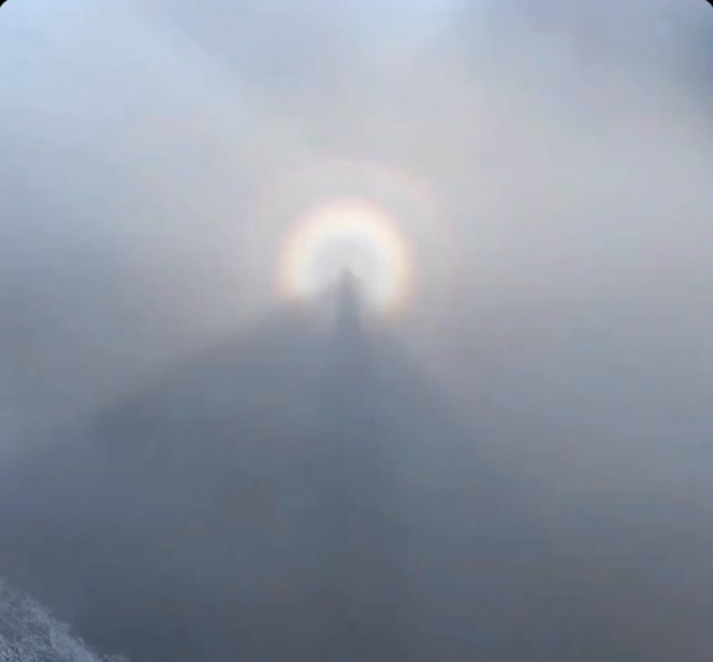 A hiker captures his own shadow floating in the mountain mist, surrounded by a bright solar halo. An unusual but completely natural phenomenon.