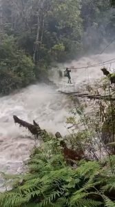 A man crossing an extremely dangerous overflowing bridge