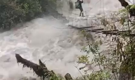 A man crossing an extremely dangerous overflowing bridge