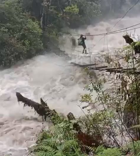 A man crossing an extremely dangerous overflowing bridge