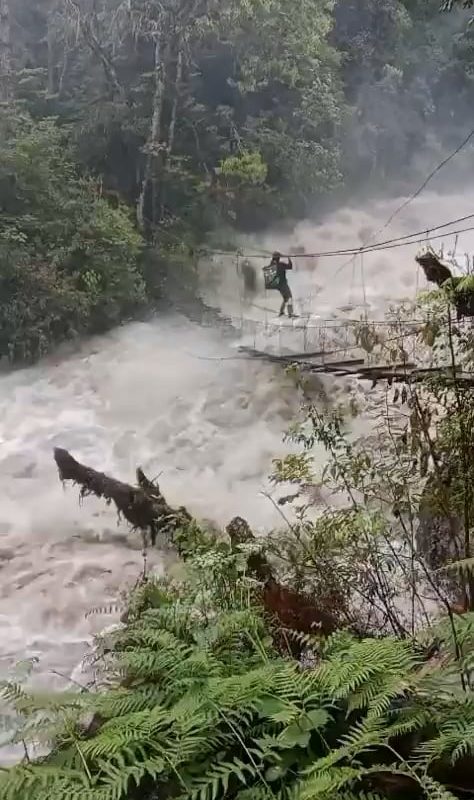 A man crossing an extremely dangerous overflowing bridge