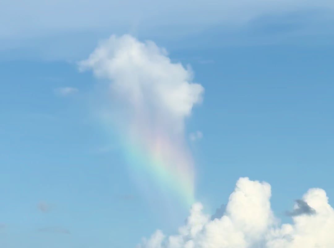 Caught a cloud raining a rainbow onto another cloud