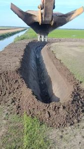Digging trench with excavator fitted with a V-shaped bucket