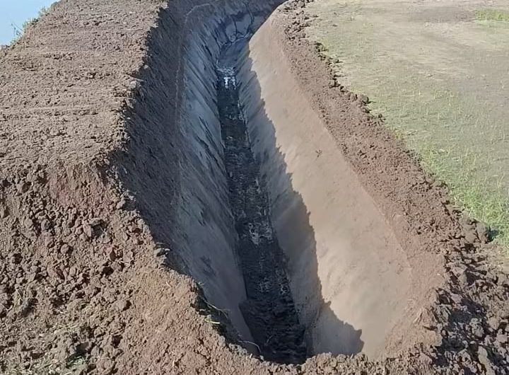 Digging trench with excavator fitted with a V-shaped bucket
