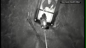 Drone drops a life jacket to a man on top of a car surrounded by flood