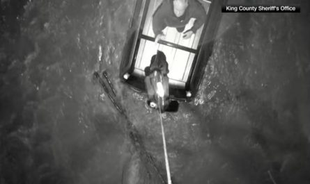 Drone drops a life jacket to a man on top of a car surrounded by flood