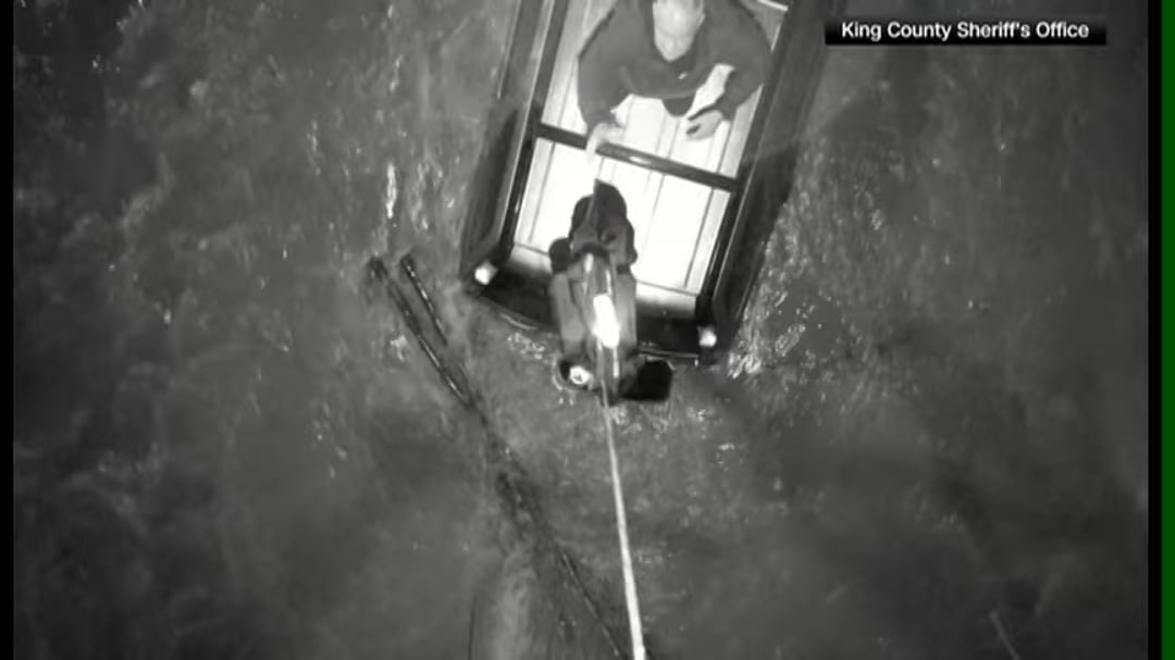 Drone drops a life jacket to a man on top of a car surrounded by flood