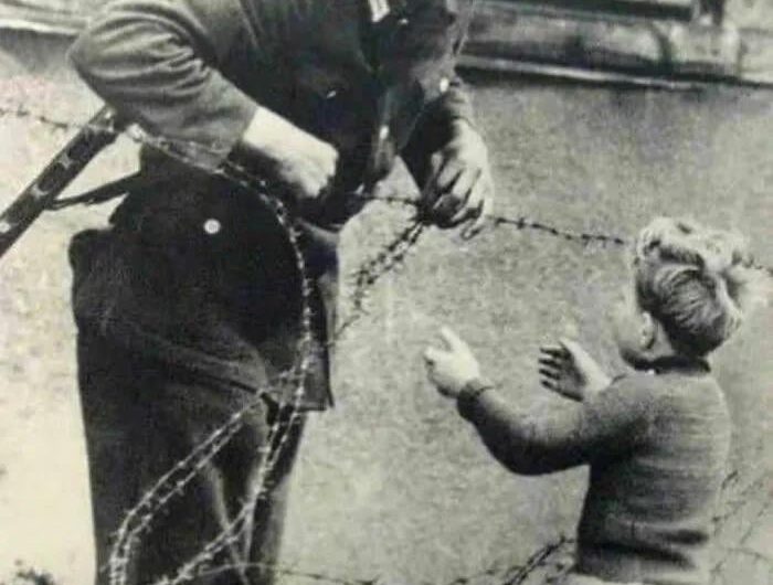 East German soldier helps a little boy sneak across the Berlin Wall the day it was erected in 1961. The boy had been left behind in the chaos of people fleeing to be with their families on either side of the wall.