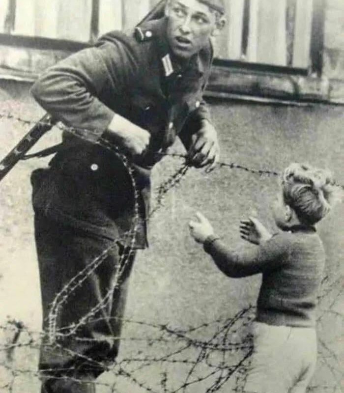 East German soldier helps a little boy sneak across the Berlin Wall the day it was erected in 1961. The boy had been left behind in the chaos of people fleeing to be with their families on either side of the wall.