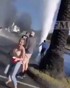 Group attempts a daring stunt with a burst water pipe geyser.