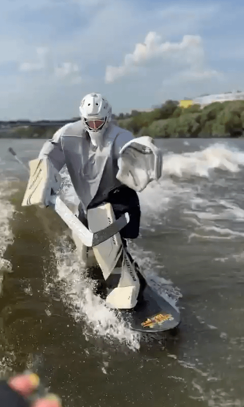 Hockey goalie coach surfing off boat