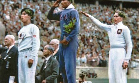 Jesse Owens salutes during the presentation of his gold medal for the long jump, after defeating Germany’s Lutz Long during the 1936 Summer Olympics in Berlin (1936) [Colourised]