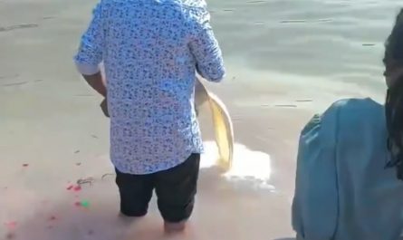 Man performs milk-offering ritual in the Ganges river in India while poor hungry children try to collect it to drink.