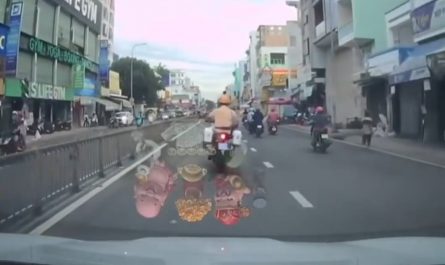 Motorbike cop maneuvering through heavy traffic in Vietnam to escort a woman in labor to the hospital