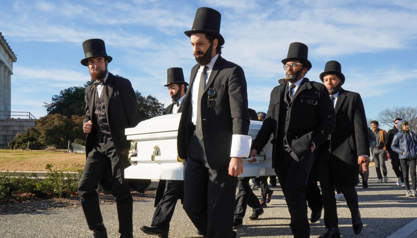 People dressed as Lincoln carrying a casket for the penny at the Lincoln Memorial