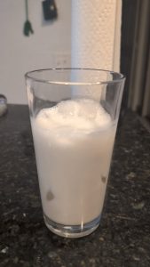 Pouring a shaken espresso shot over iced oat milk