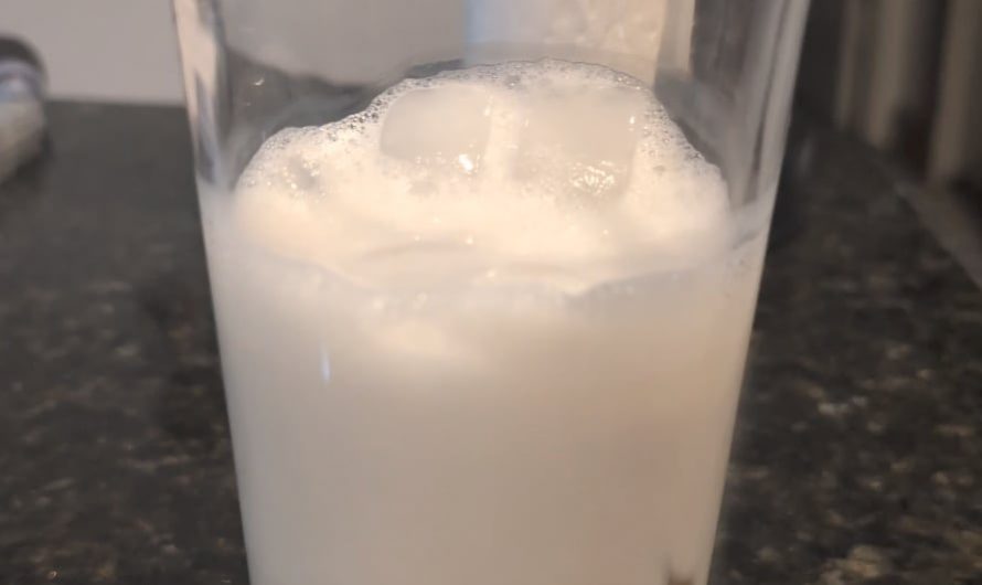 Pouring a shaken espresso shot over iced oat milk