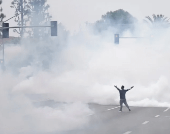 Protestor in LA stands in a cloud of tear gas