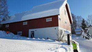Removing snow from roof with a rope in Norway