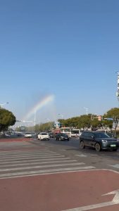 The sprinkler truck leaves a rainbow in its wake.