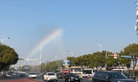 The sprinkler truck leaves a rainbow in its wake.