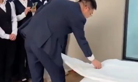 This man shows new hotel staff how to make a bed