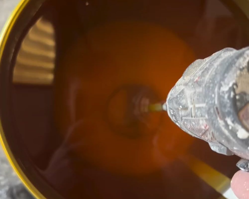 Stirring a drum of wood lacquer that’s been sitting for a while