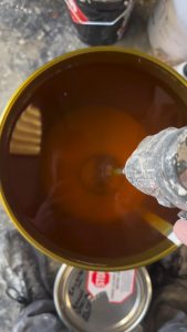 Stirring a drum of wood lacquer that’s been sitting for a while