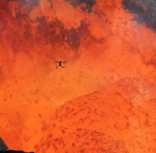 A drone flying above an erupting volcano shows the scale of the lava fountain below