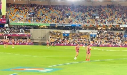 A kid runs on the field at an Australian Rules Football game and security cannot catch him