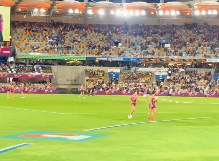 A kid runs on the field at an Australian Rules Football game and security cannot catch him