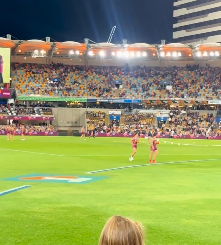 A kid runs on the field at an Australian Rules Football game and security cannot catch him