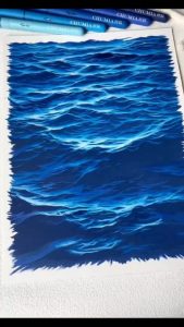 Artist is drawing realistic ocean waves using colored pens.
