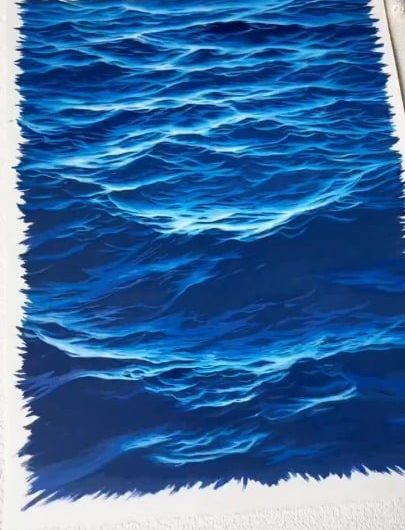 Artist is drawing realistic ocean waves using colored pens.